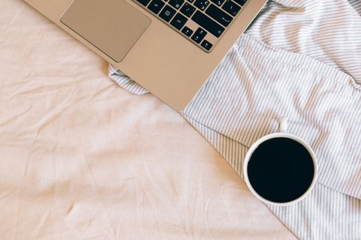Top view of a laptop and coffee on a striped blanket, creating a cozy workspace.