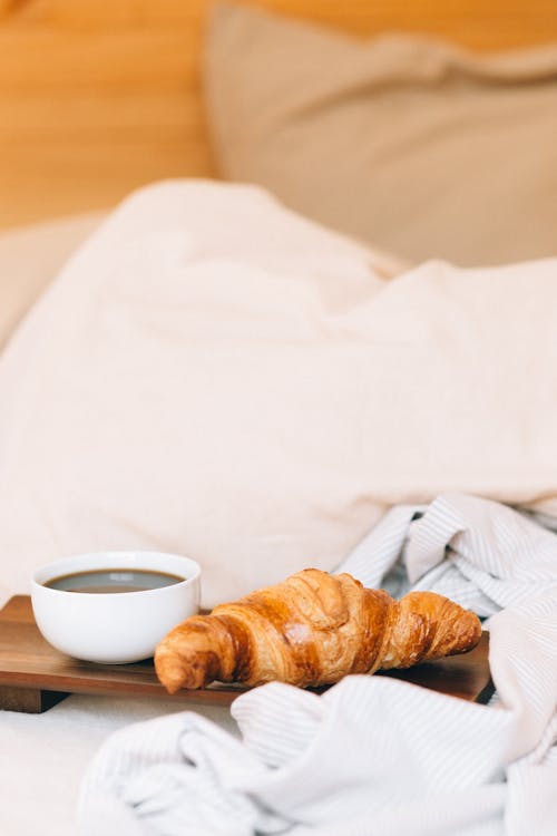 A Cup of Black Coffee and a Croissant on a Wooden Tray