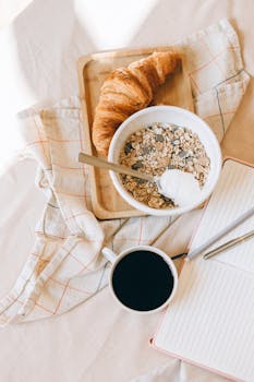 Top view of a breakfast setup with cereal, coffee, and a croissant on a tray.