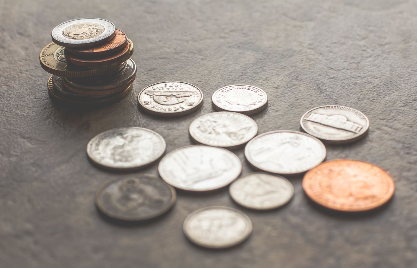 Assorted foreign coins stacked and scattered on a textured surface.