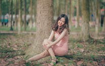 一位面带微笑的年轻女子坐在公园阳光明媚的树上，享受着休闲时光