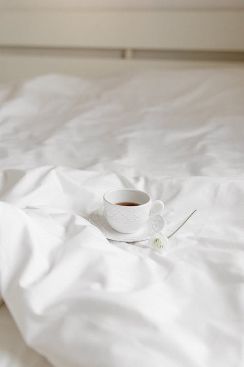 A Cup on a Saucer on the White Blanket