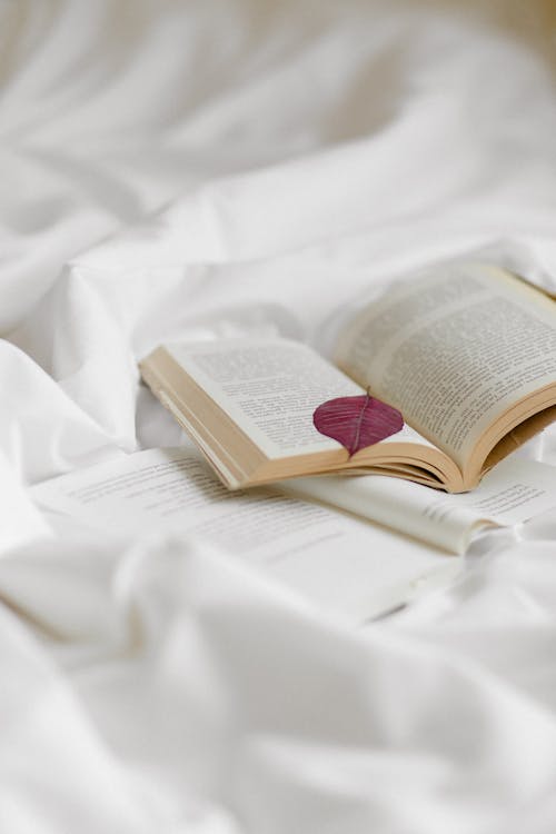 Free Open Book on White Bed Linen Stock Photo