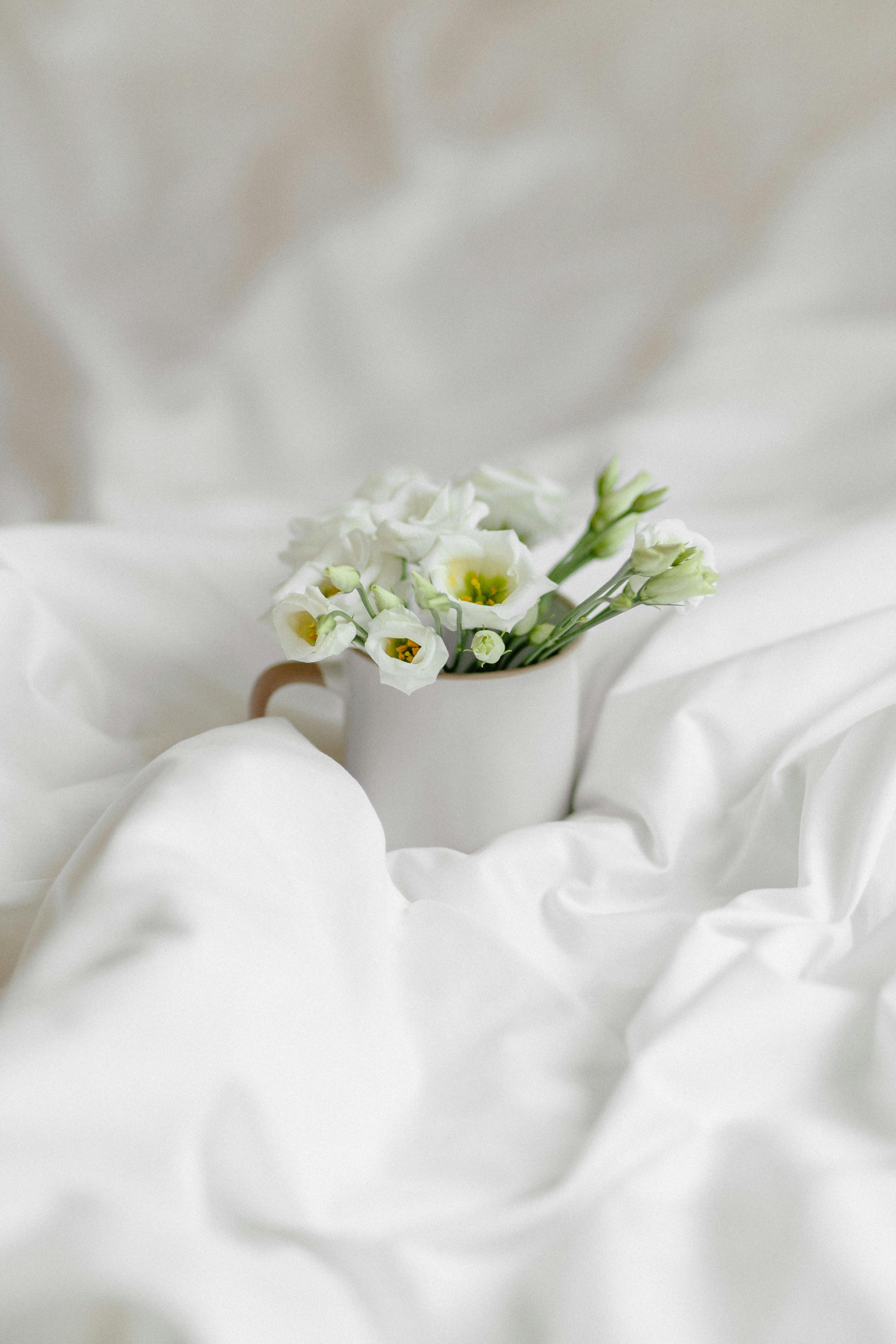 Aesthetic white flowers in a mug on a soft linen backdrop, conveying serenity and elegance.
