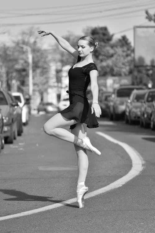 A Woman Dancing on the Road in Grayscale Photography
