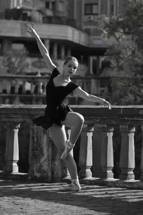Free Ballet dancer striking a graceful pose in an outdoor urban setting, captured in black and white. Stock Photo