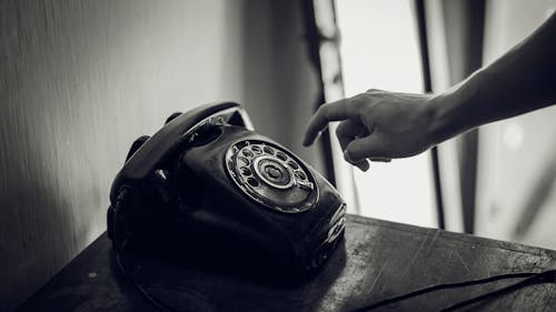Free Grayscale Photo of Rotary Telephone Beside Person Hand Stock Photo