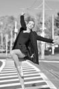 A Grayscale Photo of a Woman in Black Coat and Black Skirt Dancing on the Street