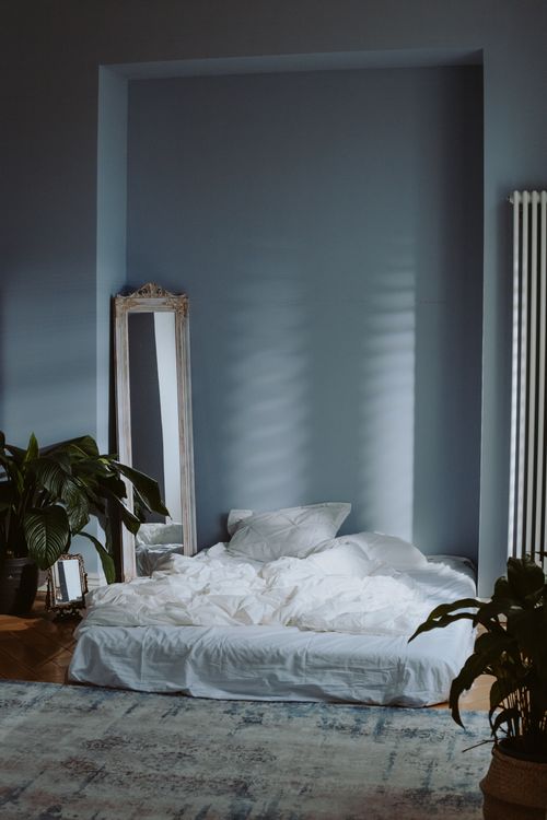 Free A serene and minimal bedroom interior with soft lighting and green plants, perfect for a peaceful atmosphere. Stock Photo