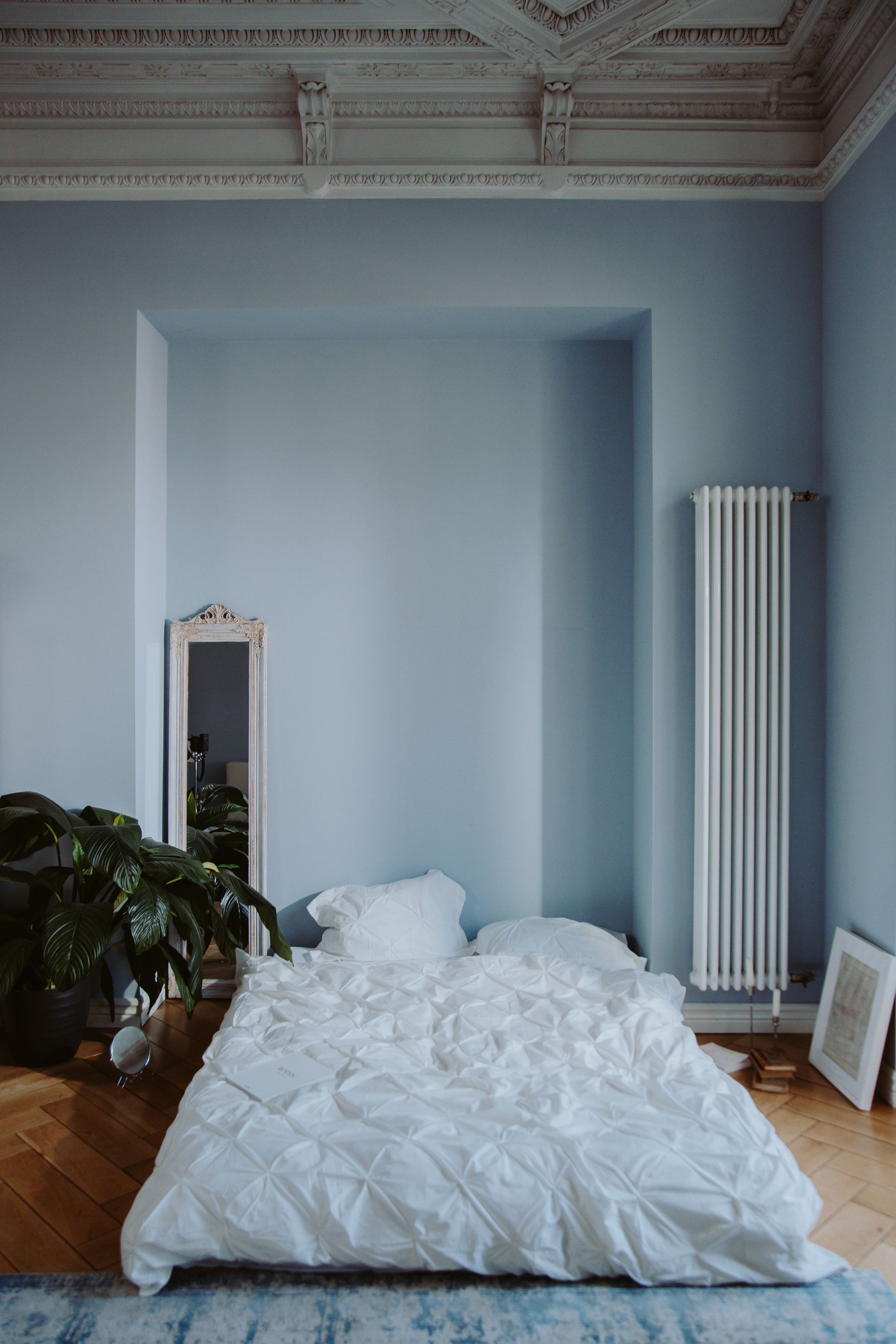 Calm light bedroom with neutral bedding, wood and green plants