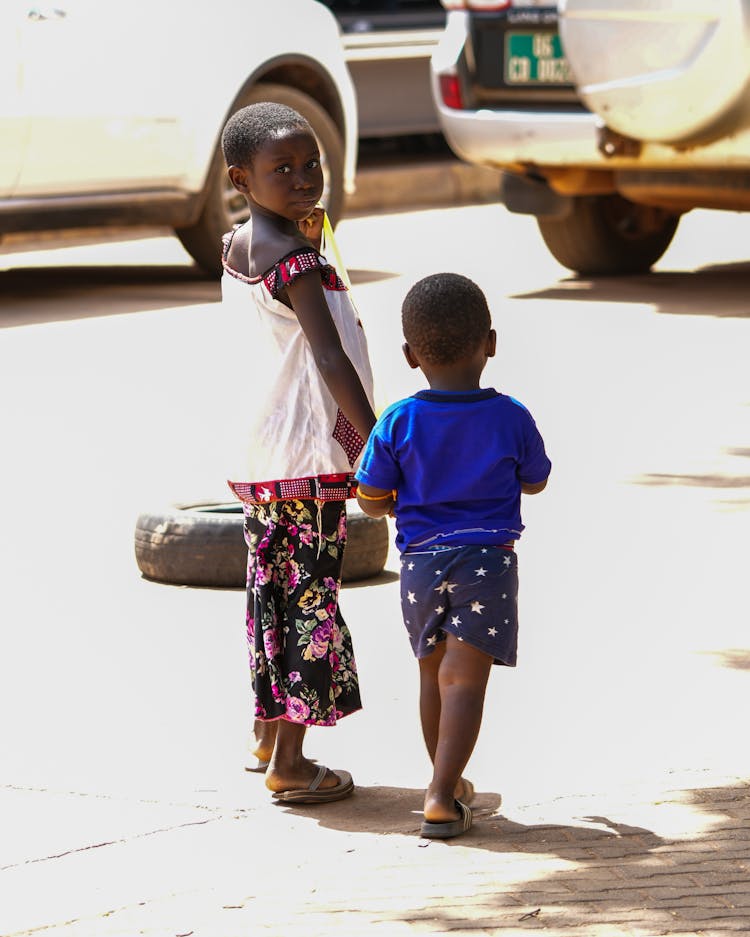 A Young Boy And Girl Walking On The Street