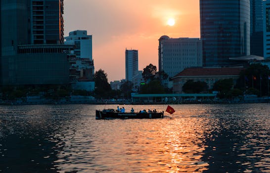 日落时分，船只航行在河上，与摩天大楼的天际线相映，展现了充满活力的城市生活
