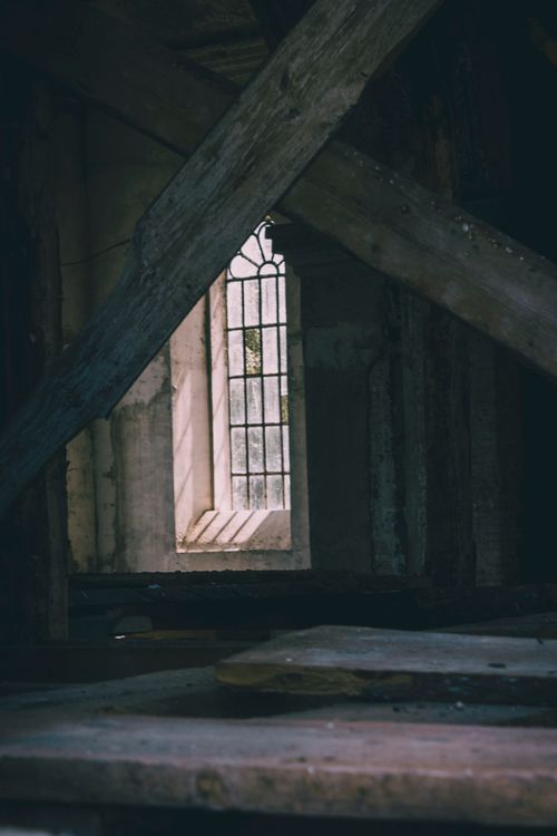 Free Moody shot of sunlight streaming through a gothic-style window in a decaying abandoned building. Stock Photo