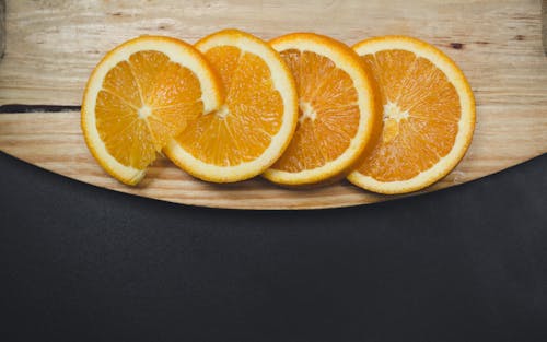 Sliced Orange Fruit on Brown Wooden Surface