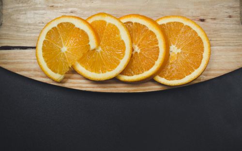 Free Close-up of fresh orange slices on a wooden board with a black background. Stock Photo