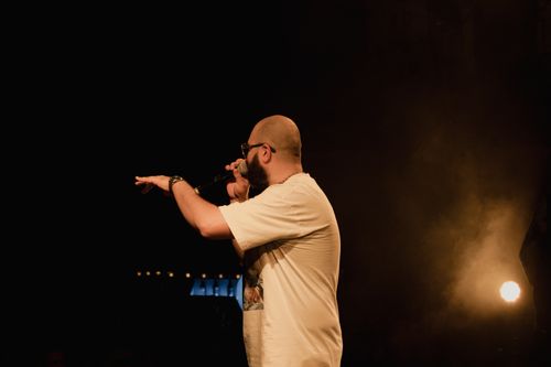 Free A man passionately performing on stage with a microphone, set against a dark background. Stock Photo