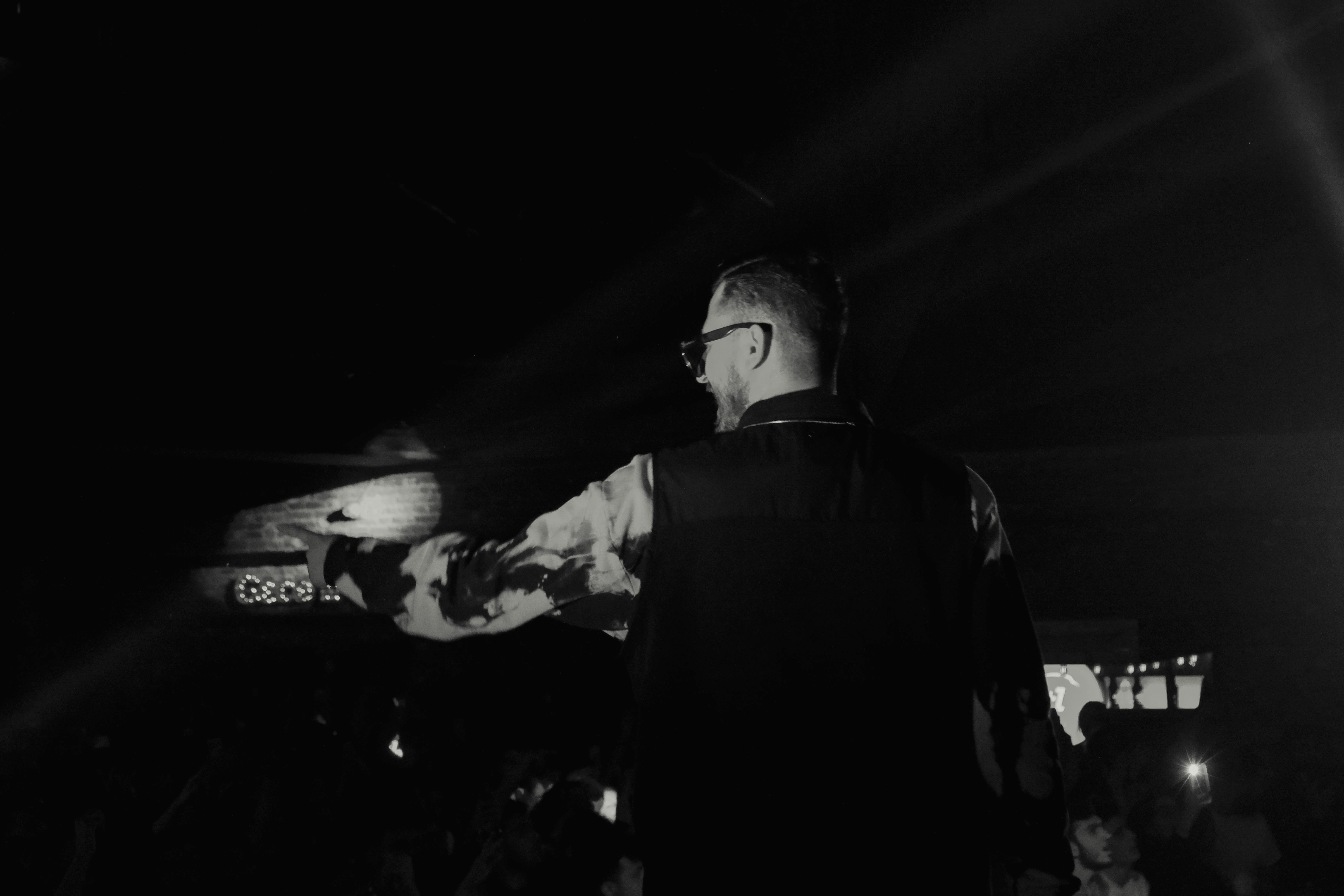 Black and white image of male singer performing on stage, creating a dramatic atmosphere.