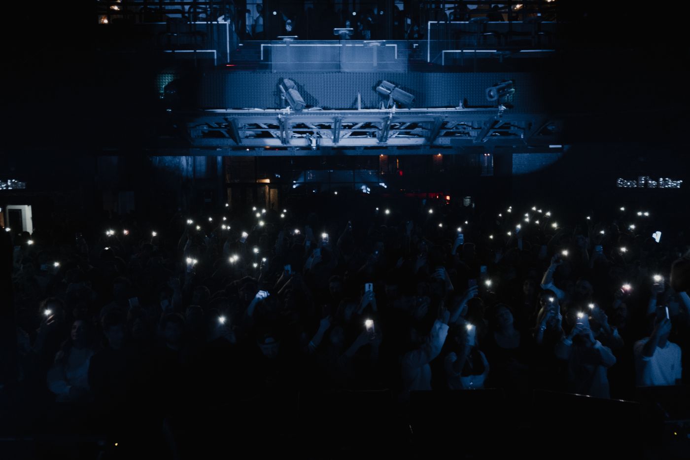 Penonton konser mengangkat ponsel saat pertunjukan musik live, menggambarkan pentingnya informasi tiket digital yang dapat diverifikasi