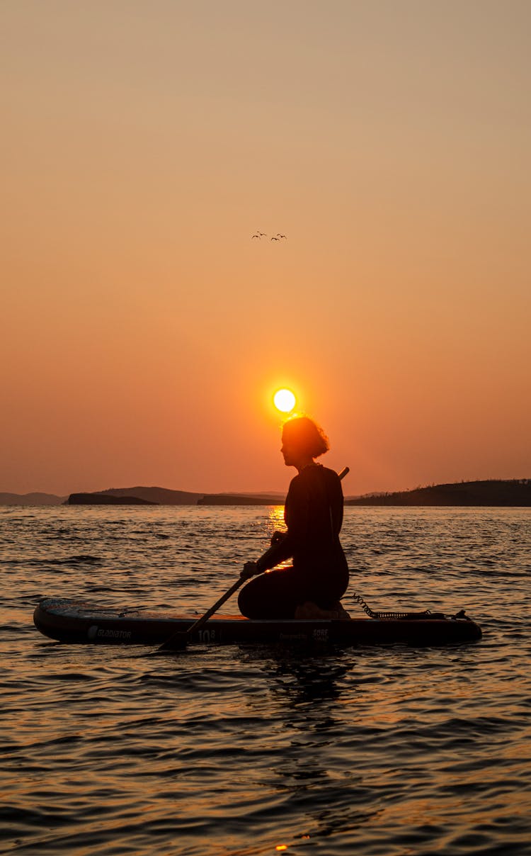 Boatman Kneeling On Primitive Boat Floating On Ocean