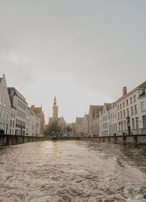 Free Captivating canal view in Bruges, Belgium with historic buildings under a stunning sunset sky. Stock Photo