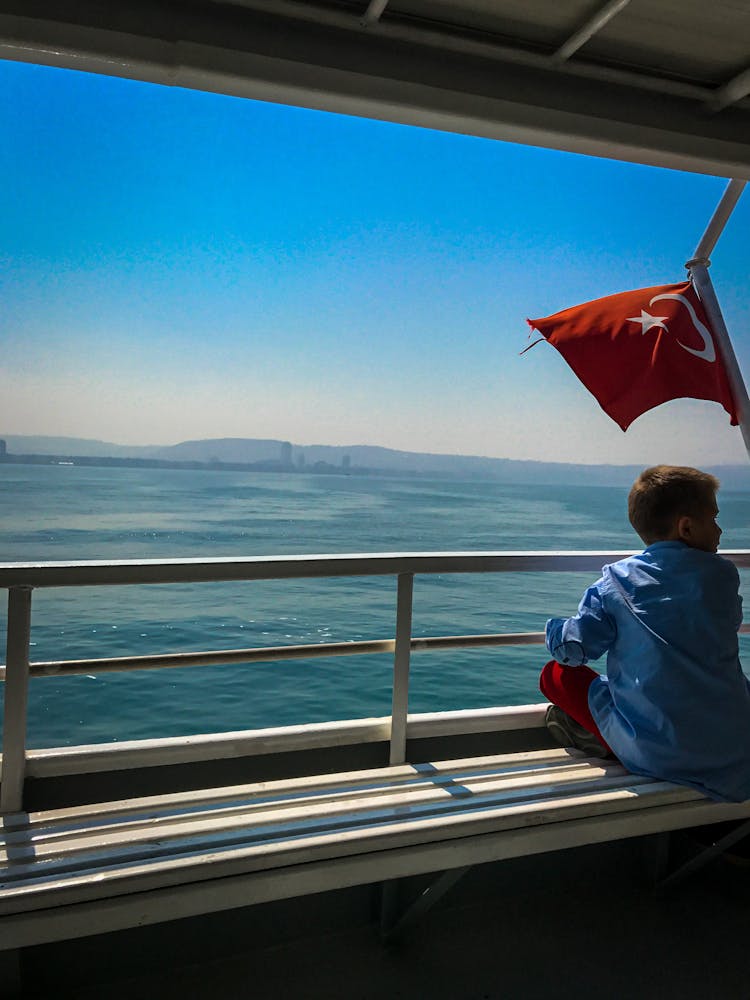 A Young Boy Sitting Near The Railings With Ocean View