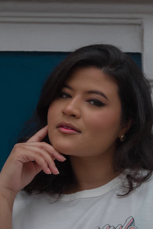 A Woman in White Shirt Looking with Her Hand on Her Chin