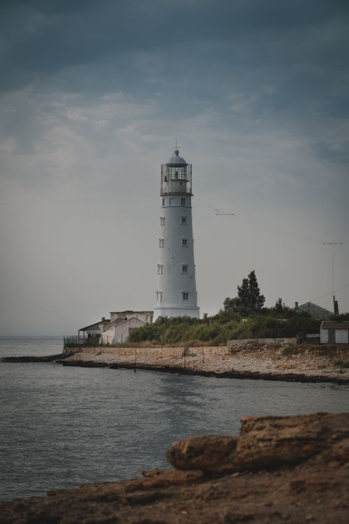 Free Scenic view of Tarkhankut Lighthouse at dusk, Crimea, with calm sea and cloudy sky. Stock Photo