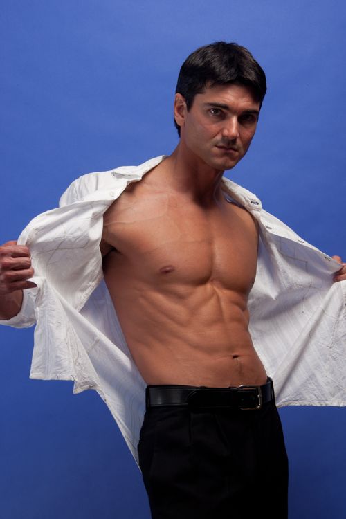 Free Muscular man in a studio setting, revealing toned physique against a blue background. Stock Photo
