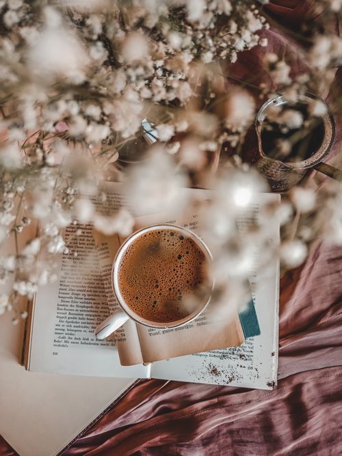 Free A warm and inviting top view of coffee, open book, and delicate flowers on a rustic surface. Stock Photo
