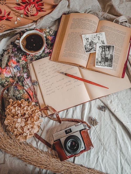 Free Open Book with Old Photos and Notepad Beside Analog Camera on Bed Stock Photo