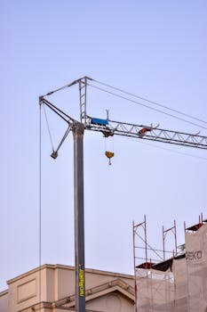 Cranes and scaffolding set against a clear blue sky during construction.