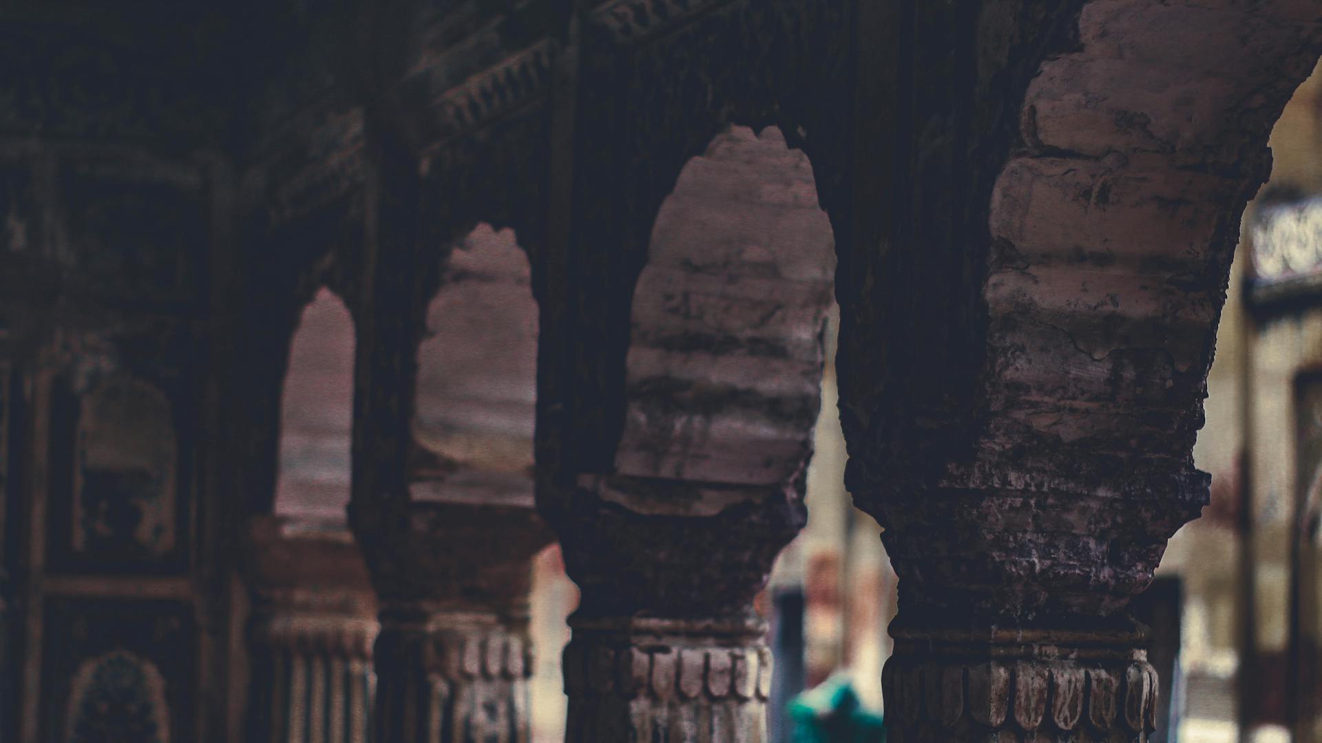 Close-up of rustic stone arches and pillars indoors, showcasing architectural texture.