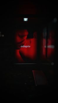 Artistic image of a couple kissing in red light, conveying romance and mystery.