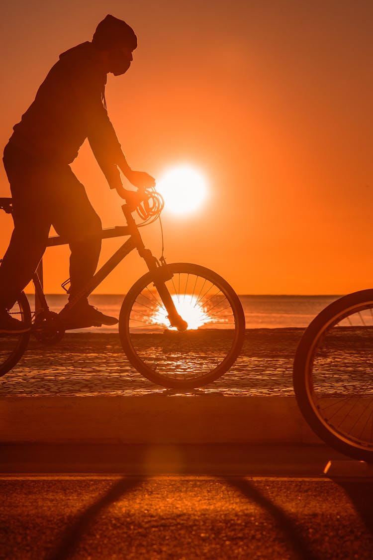 Silhouette Of Cyclist Riding Bike At Sunset