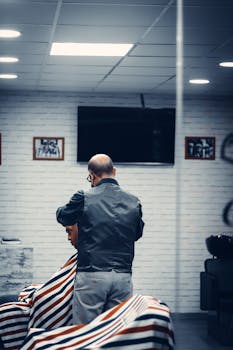 A professional barber is expertly cutting a customer's hair in a stylish barbershop interior.