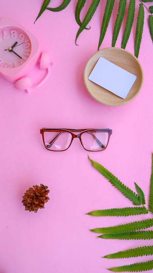 Free Eyeglasses and Green Leaves on Pink Background Stock Photo