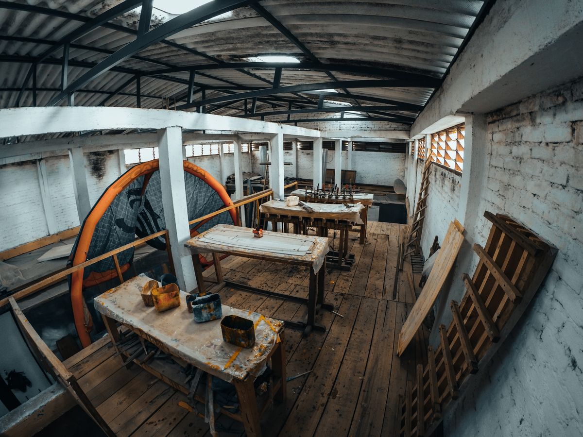 Traditional Aussie shed interior with dim natural light, visible wooden work tables and exposed metal roof trusses, showing how poorly lit most sheds are before an upgrade
