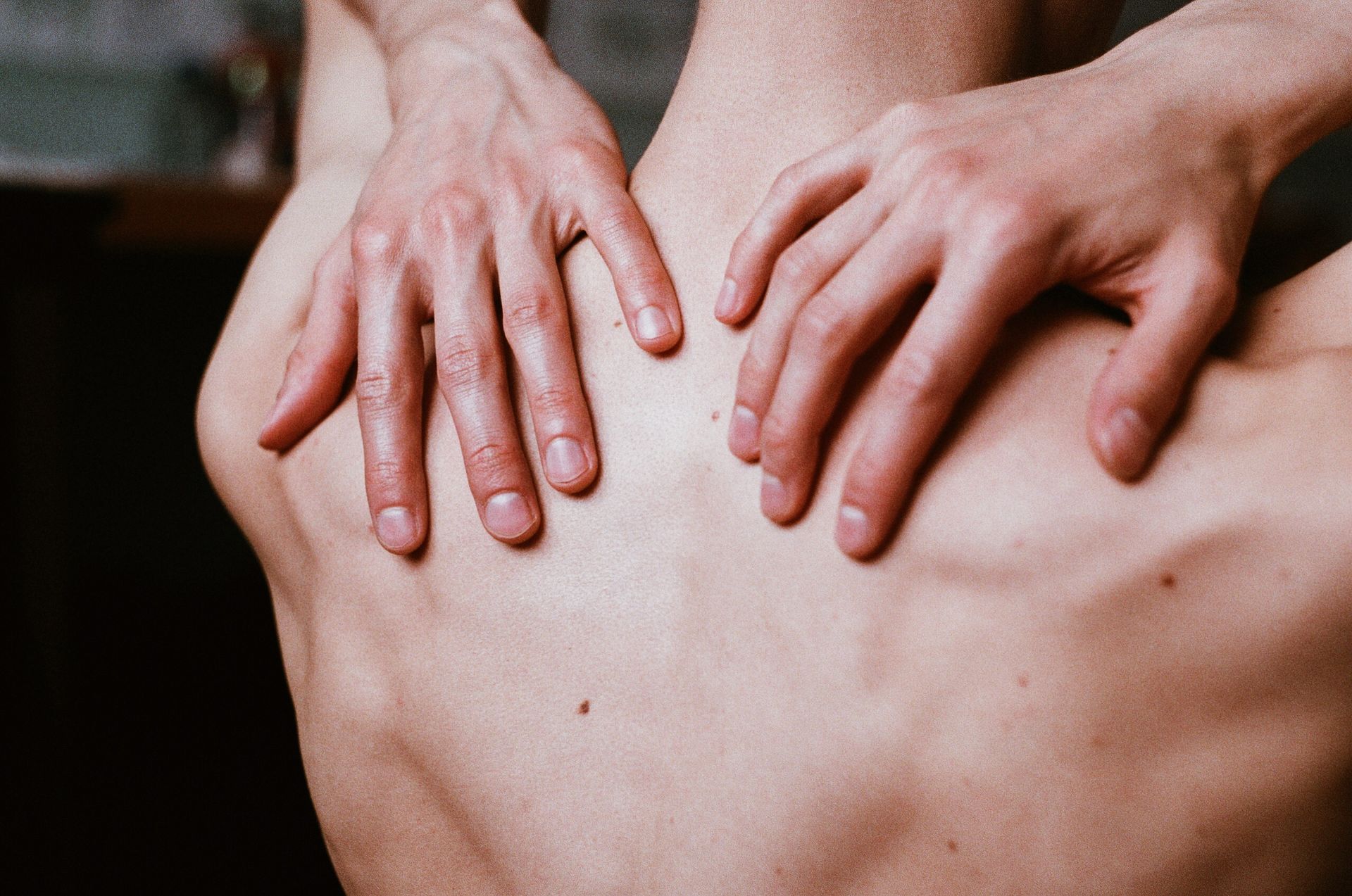 Aesthetic close-up shot of man's hands placed on his bare back, creating a calming and contemplative image.