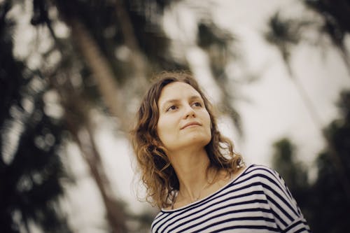 Woman in Striped Top Looking Away Beside Palm Trees