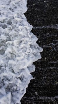 Close-up of ocean waves crashing on a rocky beach, creating sea foam on a summer day.