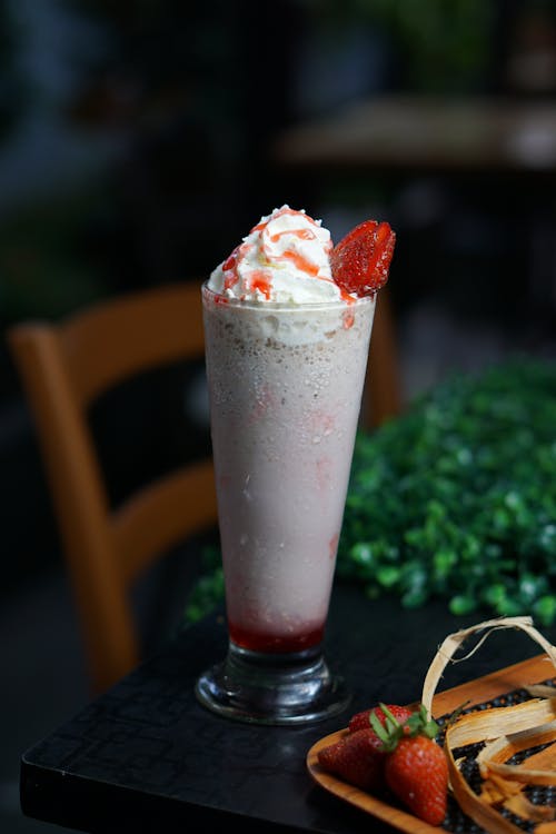 A Glass of Strawberry Milkshake with a Piece of Strawberry on Top