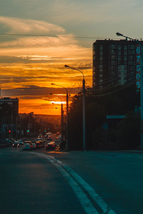 Free Sunset view with city buildings, cars, and streetlights creating a picturesque urban evening scene. Stock Photo