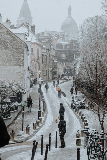 Pedestrians walking in a snow-covered street in a European town, capturing winter ambiance.
