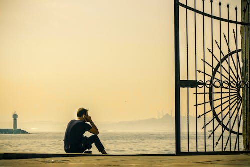 Man Using Smartphone While Sitting by the Beach