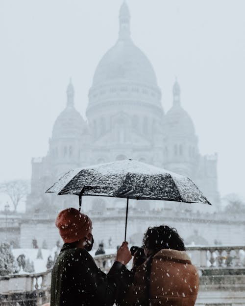 Couple Under Umbrella Looking at The Basilica of the Sacred Heart on Montmartre in Paris During Snowing