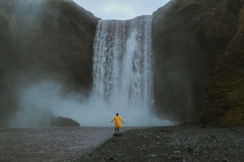 Person in Yellow Clothes by the Waterfall