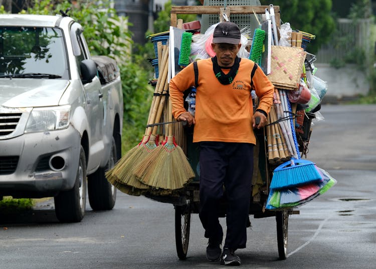 Man In Orange Jumper Pulling The Wagon With Household Goods