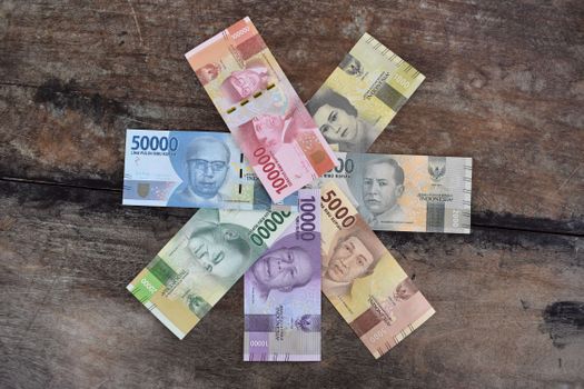Colorful Indonesian Rupiah banknotes arranged on a wooden surface, showcasing different denominations. - Fotografer Sidoarjo