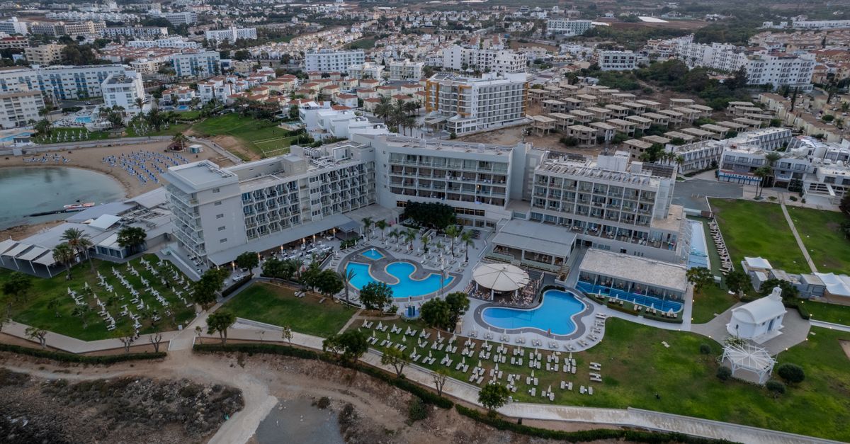 Aerial view of a luxurious resort in Pernera, Famagusta, Cyprus featuring pools and cityscape.