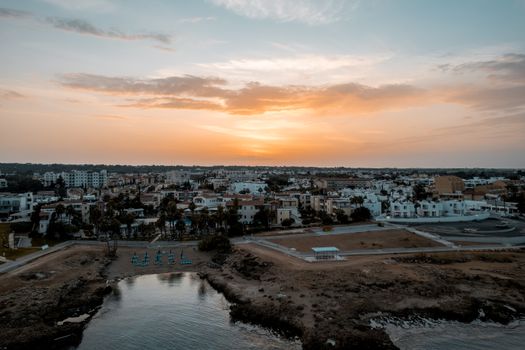 A stunning aerial view of Pernera, Cyprus, with a vibrant sunset sky over coastal cityscape.